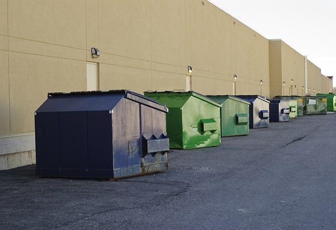 a construction worker unloading debris into a blue dumpster in Harbor City, CA